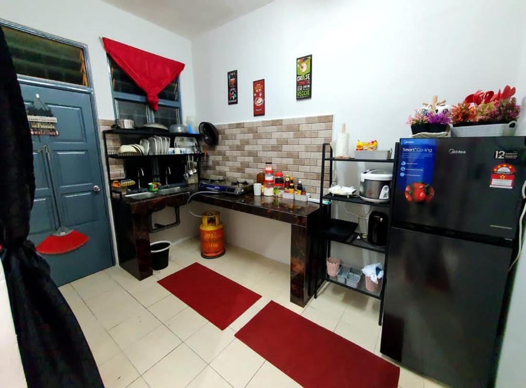 una cocina con nevera y encimera. en LH Alisha Homestay Wangsa Mewangi Gua Musang en Gua Musang