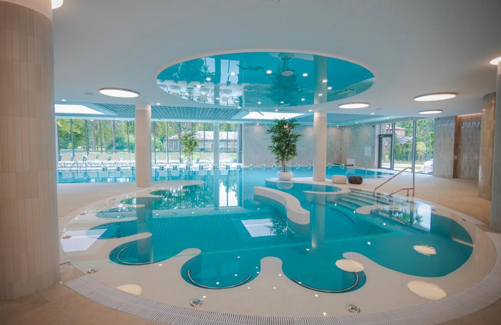 a pool in a hotel lobby with a glass ceiling at Mineral SPA Draugystė in Druskininkai