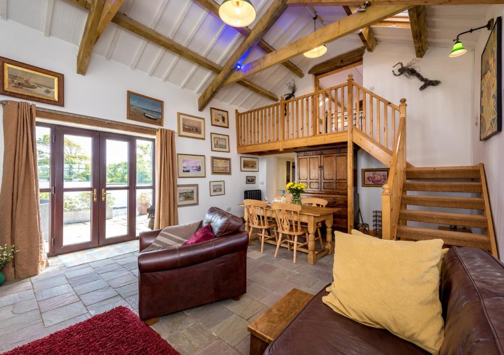 ein Wohnzimmer mit einem Sofa und einer Holztreppe in der Unterkunft The Barn in Llannor