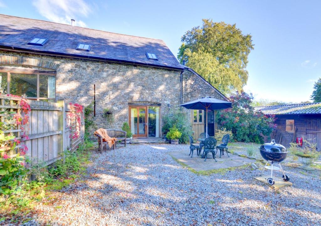 a stone house with a patio and a grill at Pipistrelle in Llansawel