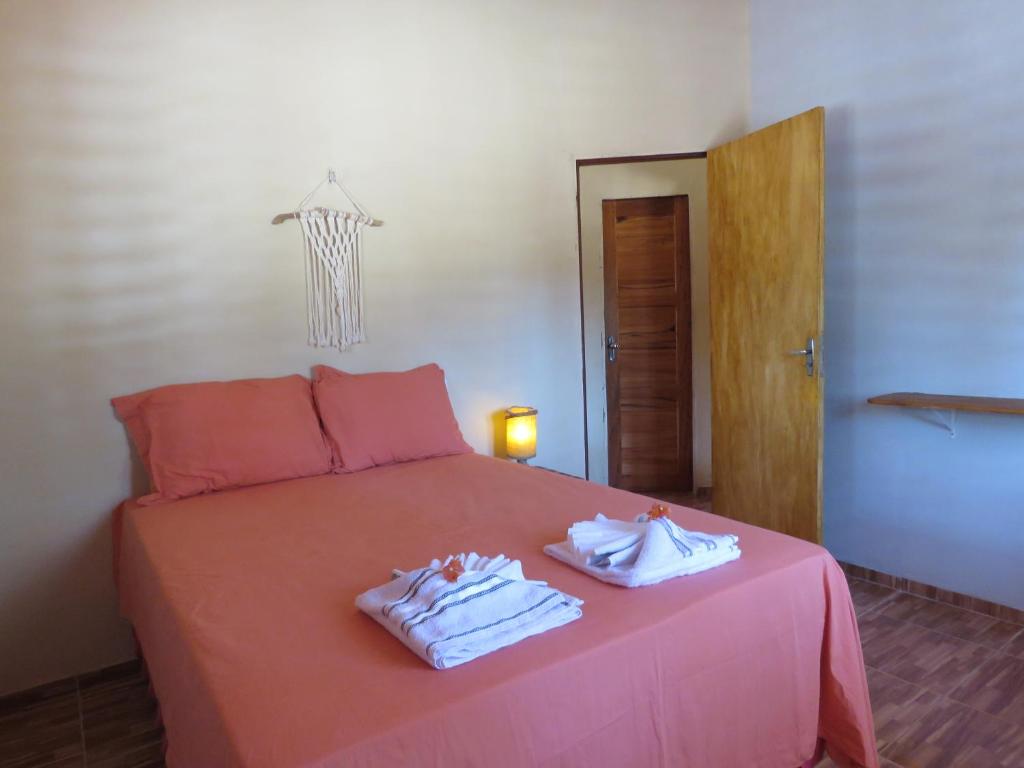 a bedroom with a pink bed with towels on it at Alameda dos Coqueirais in Icaraí