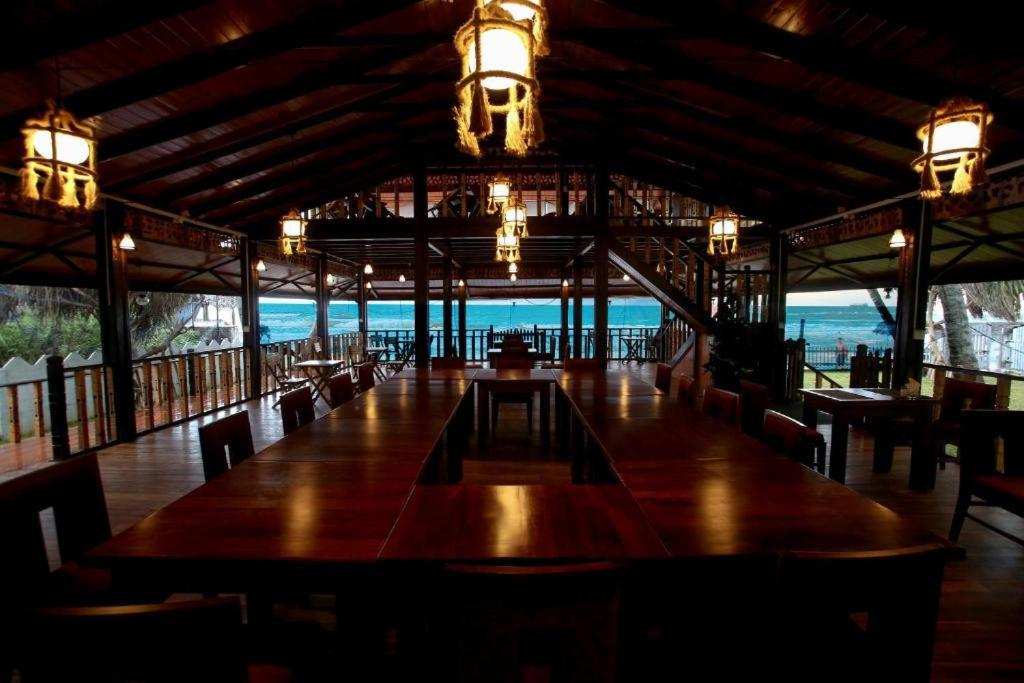 a restaurant with a long table and chairs and the ocean at Blue Sand Beach Resort in Trincomalee