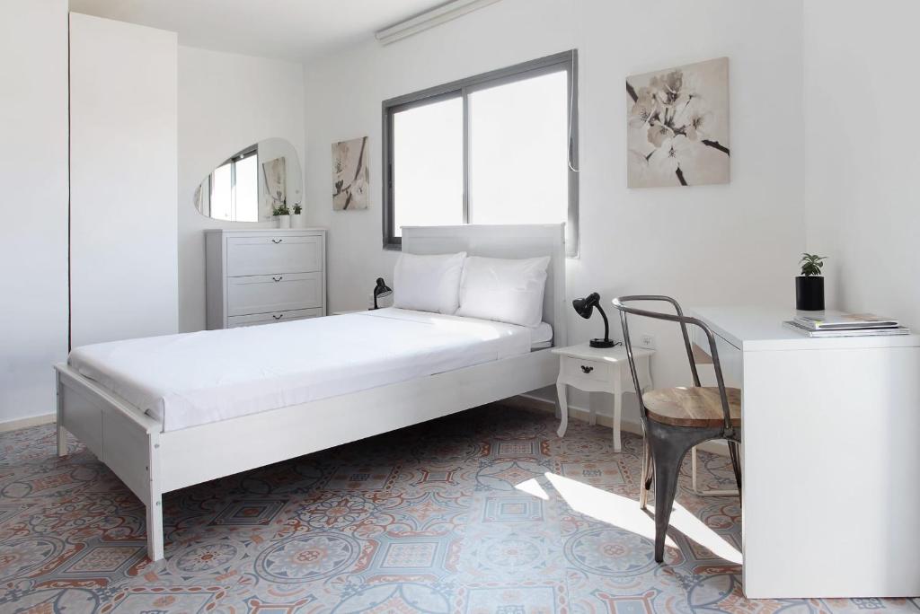 a white bedroom with a bed and a chair at Beautiful Studio in Flea Market By Holiday Rentals in Tel Aviv