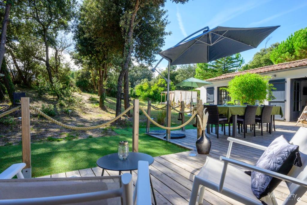 een houten terras met een tafel en een parasol bij La dune du bien etre in La Couarde-sur-Mer