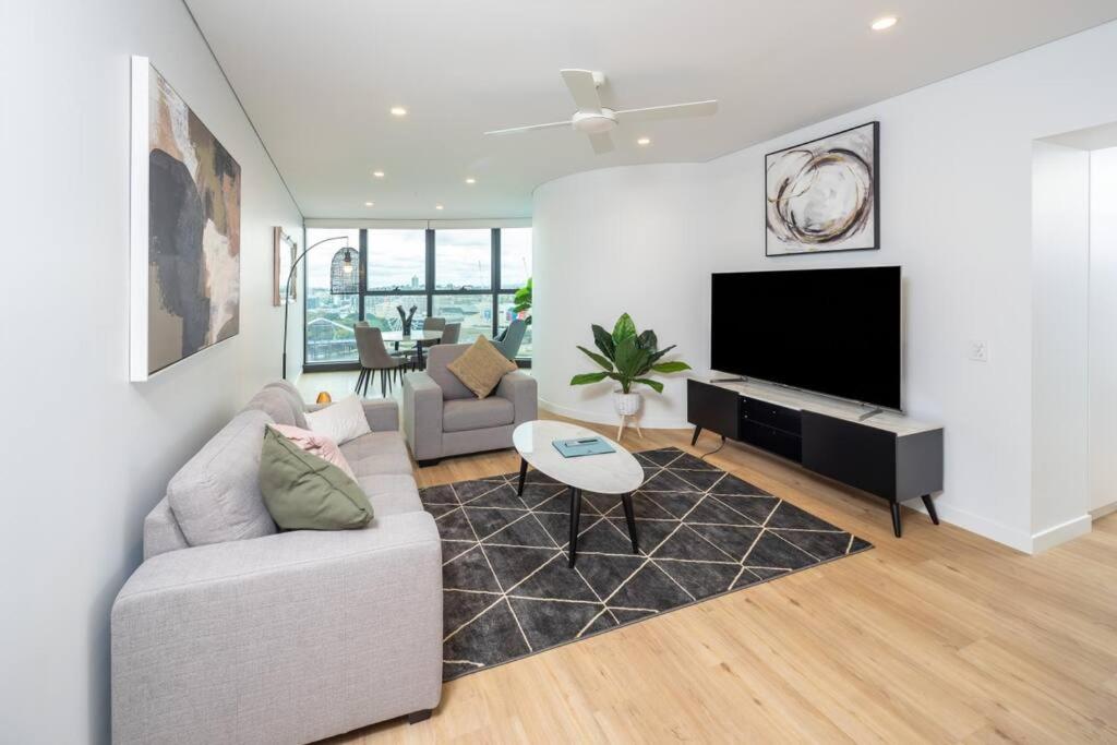 a living room with a couch and a flat screen tv at 1404 Sophistication and Luxury on the Brisbane River by Stylish Stays in Brisbane