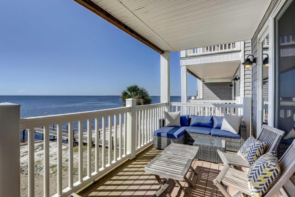 a porch with chairs and a couch and the ocean at Carrabelle Condo Beach and Fishing Pier Access in Big Blackjack Landing