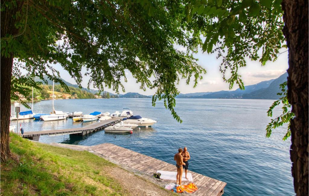 dwie osoby stojące na przystani z łodziami w wodzie w obiekcie Cozy Apartment In Carcegna Di Miasino No w mieście Pettenasco