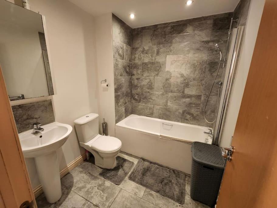 y baño con aseo, bañera y lavamanos. en Beautiful 4 bedroom home with private parking, en West Thurrock