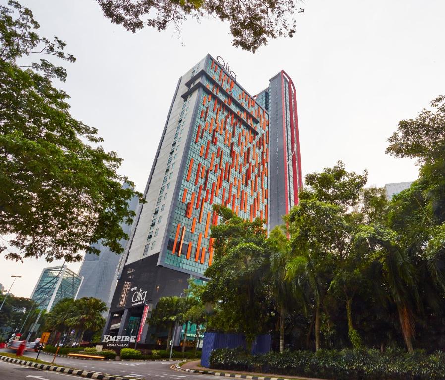 wysoki budynek z drzewami przed nim w obiekcie Qliq Damansara Hotel w mieście Petaling Jaya