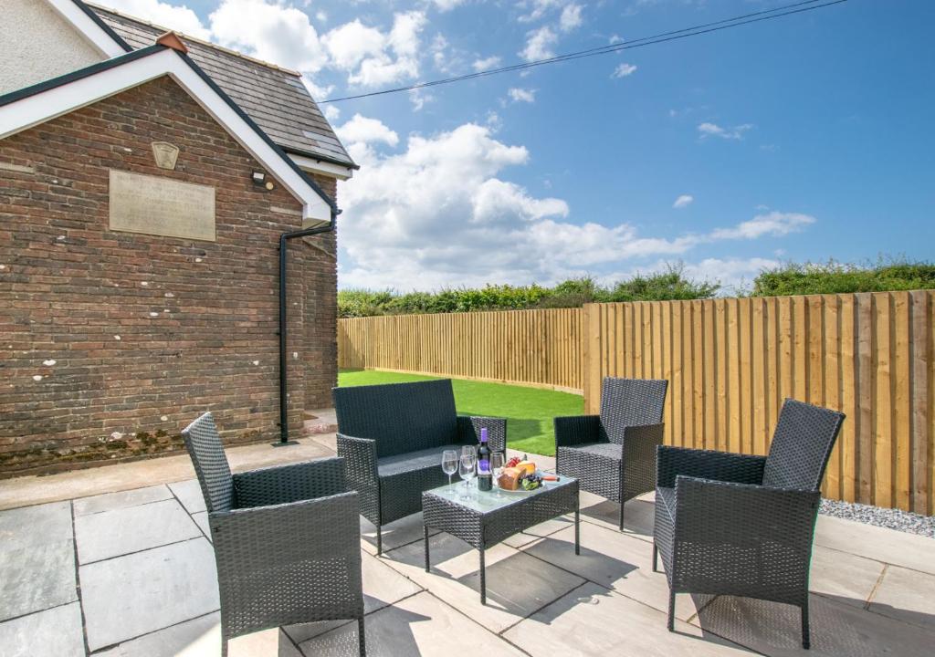 a patio with chairs and a table and a fence at The Edith in Oxwich