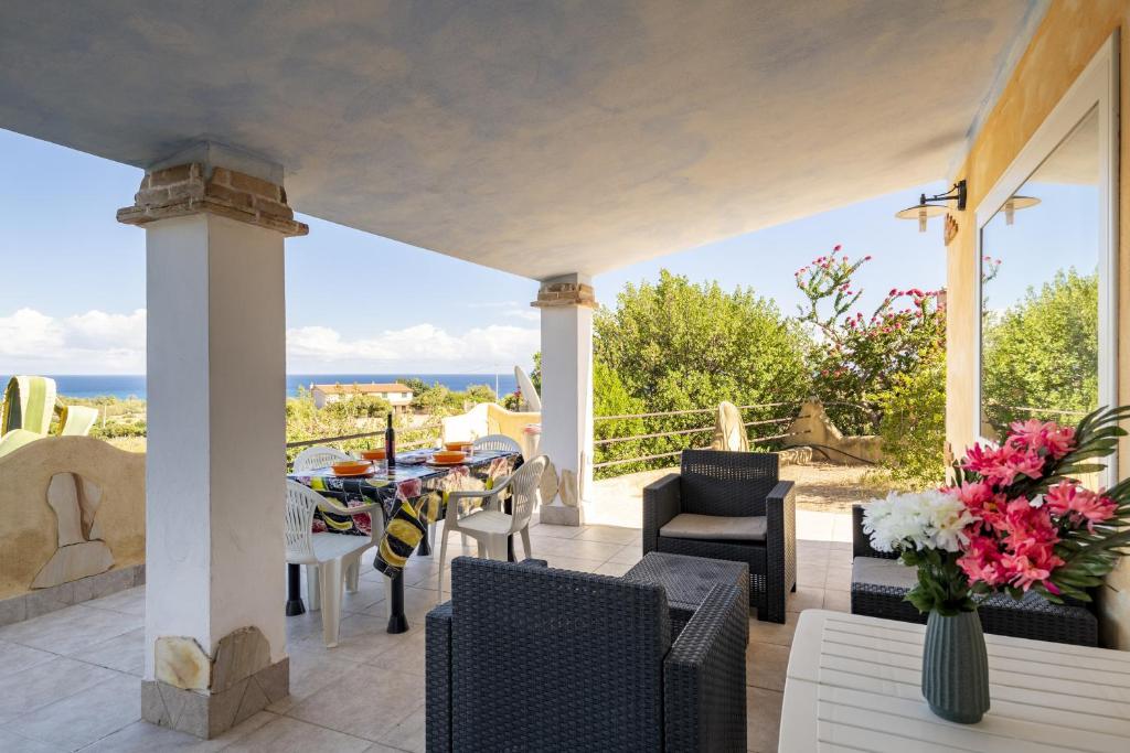 patio ze stołem i krzesłami oraz oceanem w obiekcie Villa Sole w mieście Tertenìa