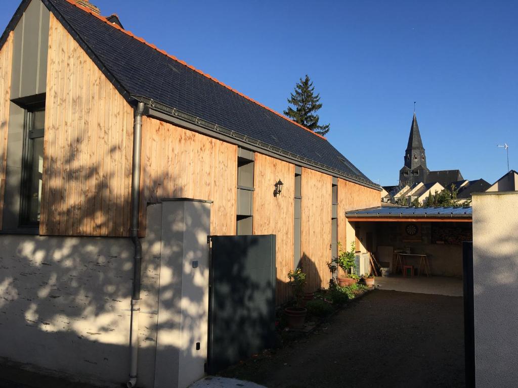 un edificio de madera con una iglesia de fondo en Chambre d'hôtes sur le chemin de la Loire à vélo en Les Ponts-de-Cé