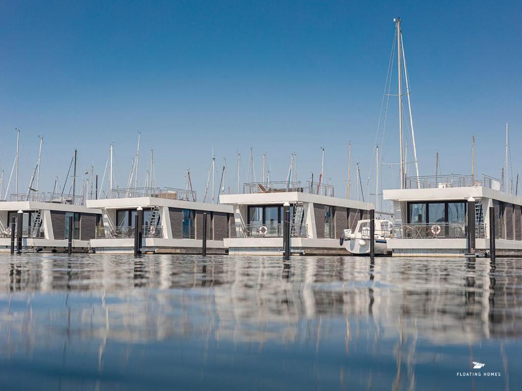 a group of boats docked at a dock in the water at Hausboot Floating Homes - A-Type Laboe FH-LA-03 Baltic Bay in Laboe