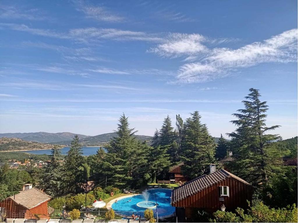 a resort with a pool and a house and trees at Cabañas Navacerrada in Navacerrada