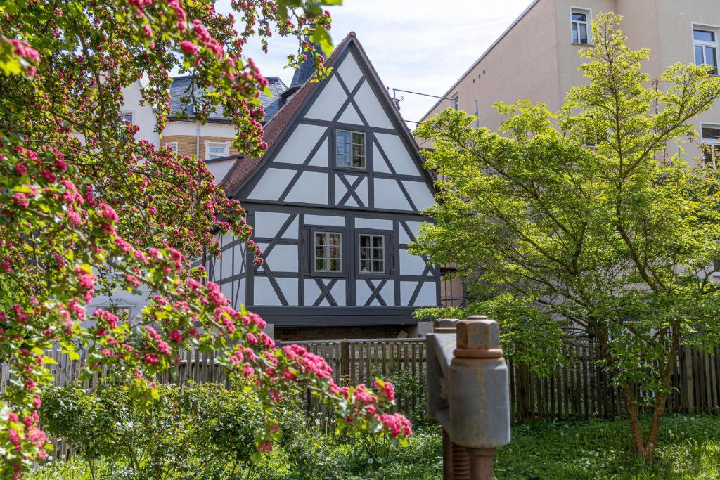 a black and white house with pink flowers at außergewöhnliches, historisches, spätgotisches Wohnhaus von 1519, Gries 5 in Gera