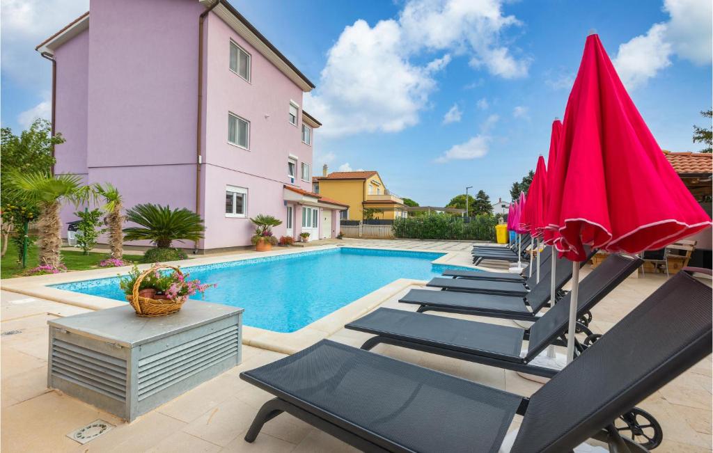 un gruppo di sedie e ombrelloni accanto alla piscina di Stunning Apartment In Valbandon With Wifi a Fažana