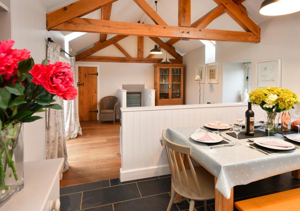 a kitchen and dining room with a table and flowers at Geufron Barn in Aberdaron