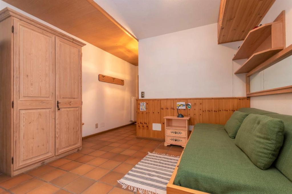 a living room with a green couch and a cabinet at Ciasa Molino 306 in Falcade