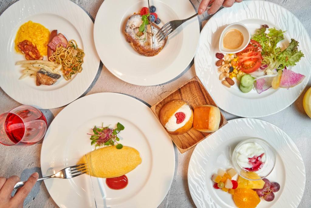 uma mesa com pratos brancos de comida em Shibuya Tokyu REI Hotel em Tóquio