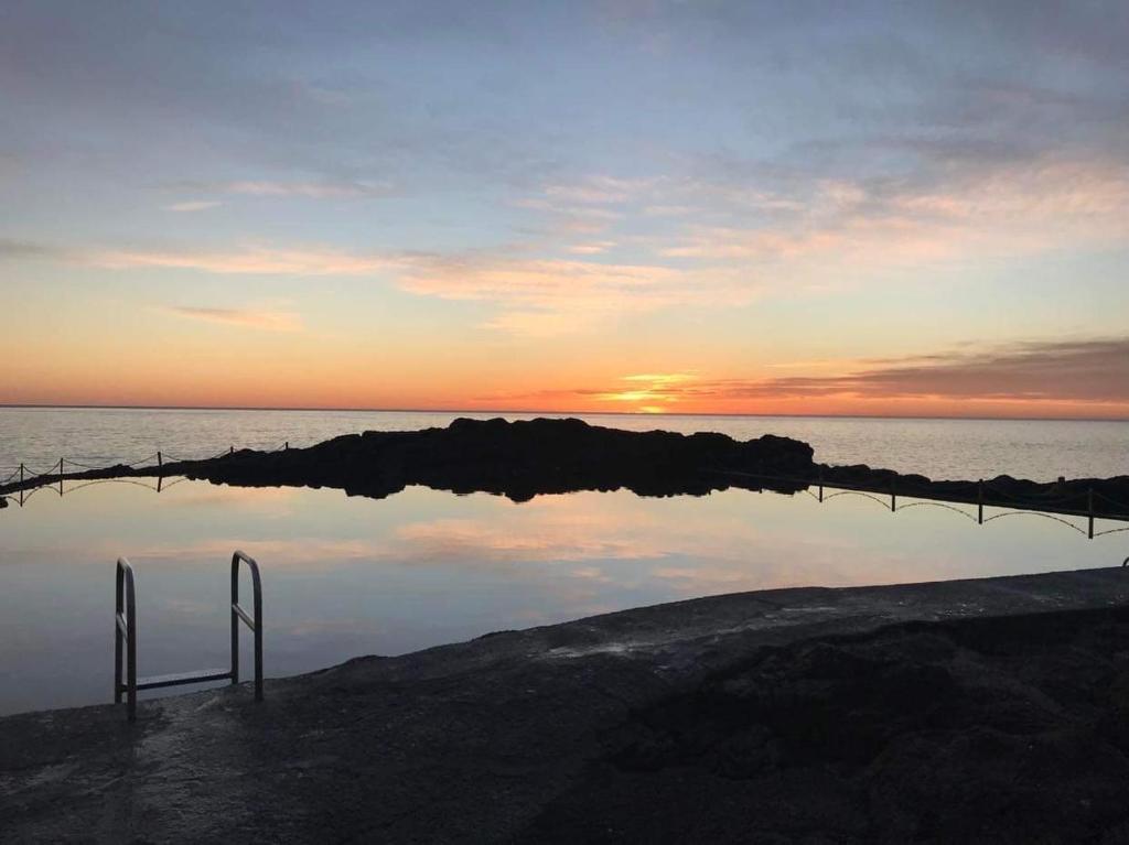 a reflection of the sunset in a body of water at The Tribe House Kiama in Kiama