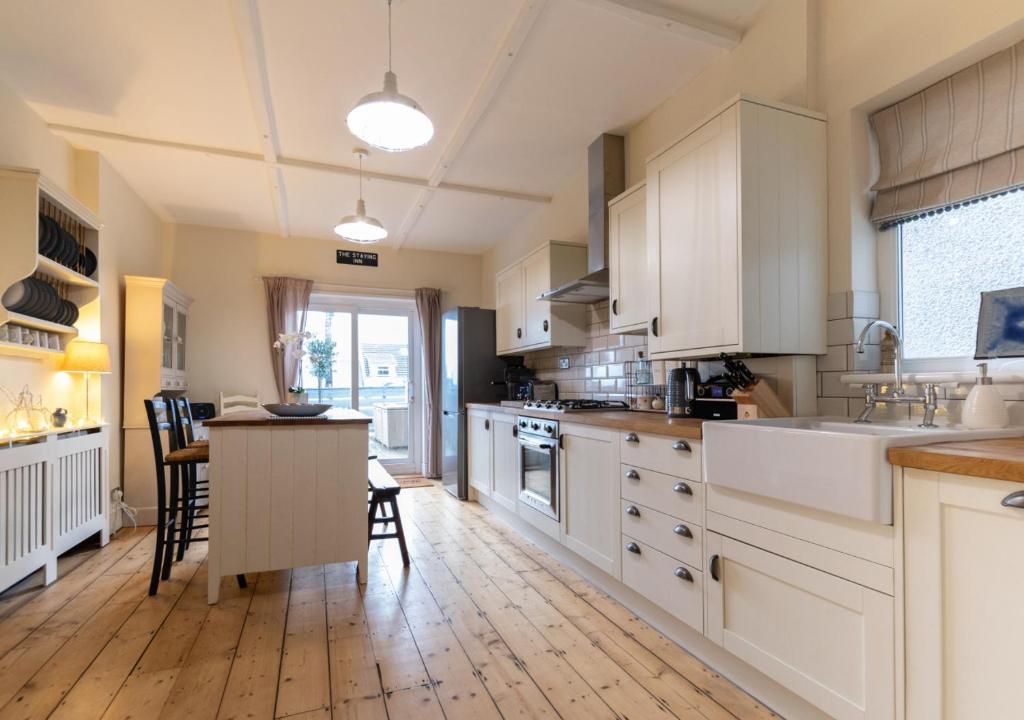 een keuken met witte kasten en een houten vloer bij Oakland House in The Mumbles