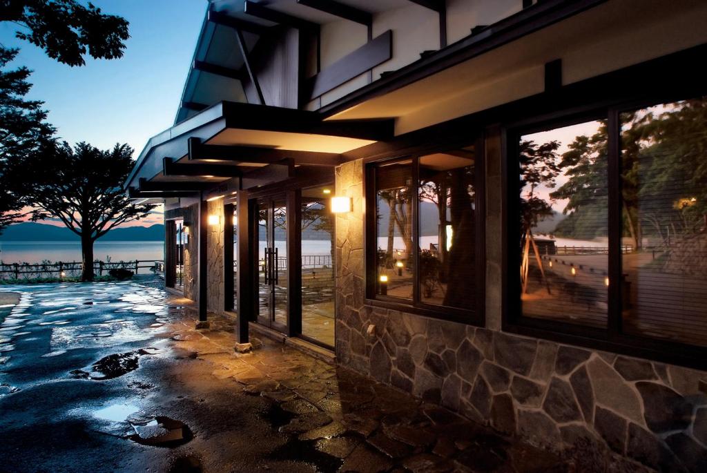 a building with windows with a view of the water at Shikotsuko Onsen Lake Side Villa SUIMEIKAKU-Adult Only in Chitose