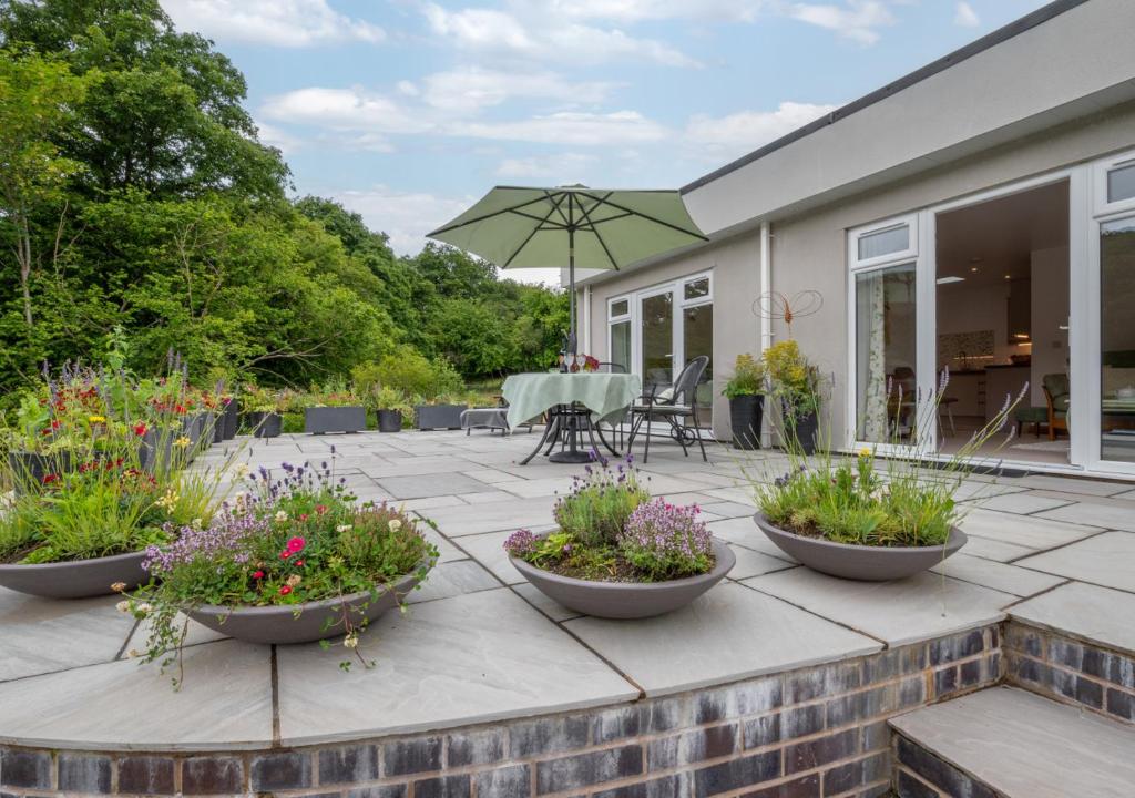 a patio with three large flower pots and an umbrella at Nyth Bryn Haul in Llanidloes