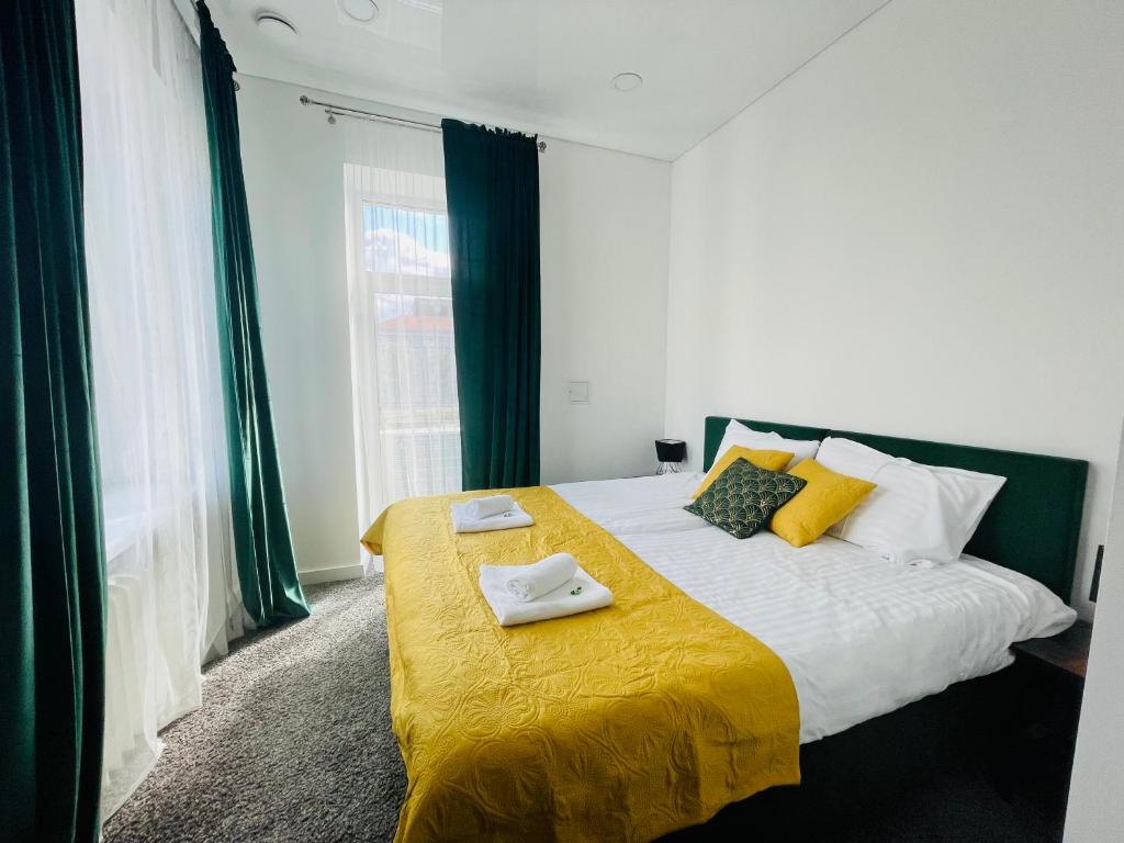 a bedroom with a bed with a yellow blanket at Green apartments Easy Kaunas in Kaunas