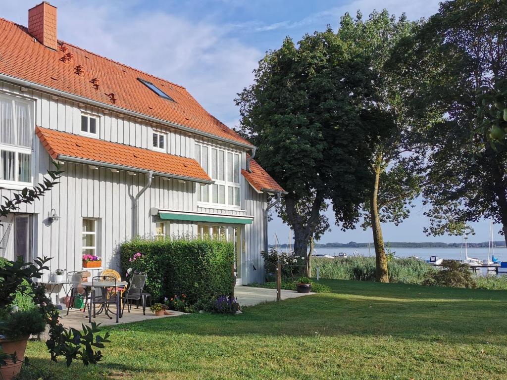 a white building with an orange roof and a yard at Ziemitz, Paradies am Peenestrom in Ziemitz