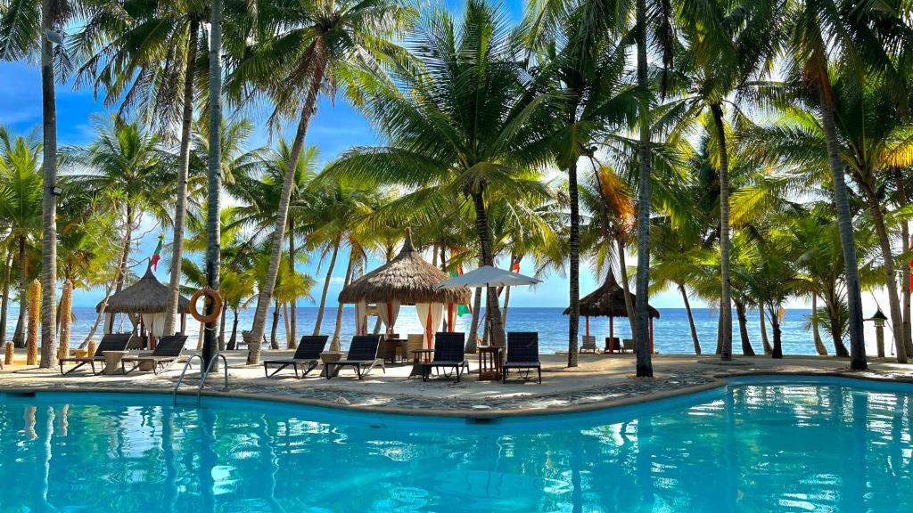 una piscina con palme, sedie e l'oceano di Coco Grove Beach Resort, Siquijor Island a Siquijor