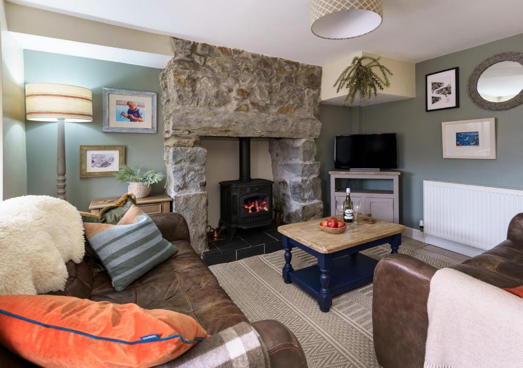 a living room with a couch and a fireplace at Marina Beach Cottage in Pwllheli