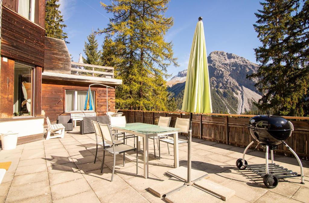 eine Terrasse mit einem Grill, einem Tisch und Stühlen in der Unterkunft Miraflor Betty by Arosa Holiday in Arosa