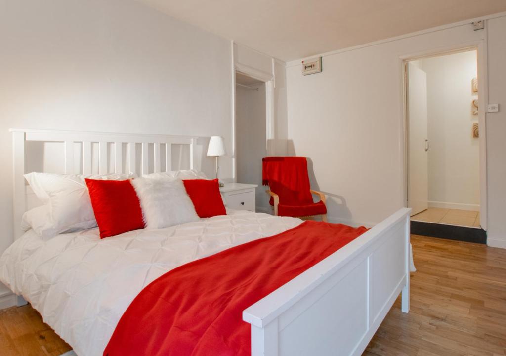 uma cama branca com almofadas vermelhas num quarto em The Cross - Y Groes em Oxwich