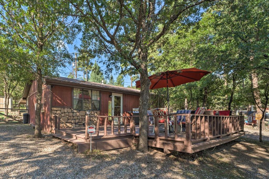 Casa con porche con sombrilla en Pet-Friendly Ruidoso Cabin Deck, Fire Pit and Grill, en Ruidoso