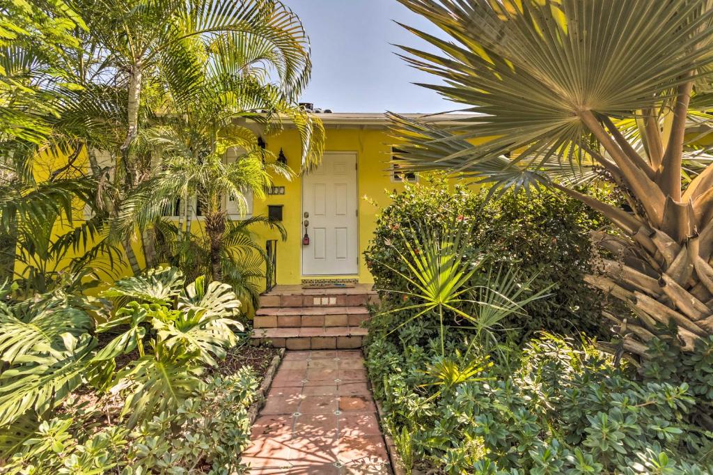 a yellow house with a white door and some palm trees at Vibrant West Palm Beach Home Less Than 2 Mi to Beach! in West Palm Beach