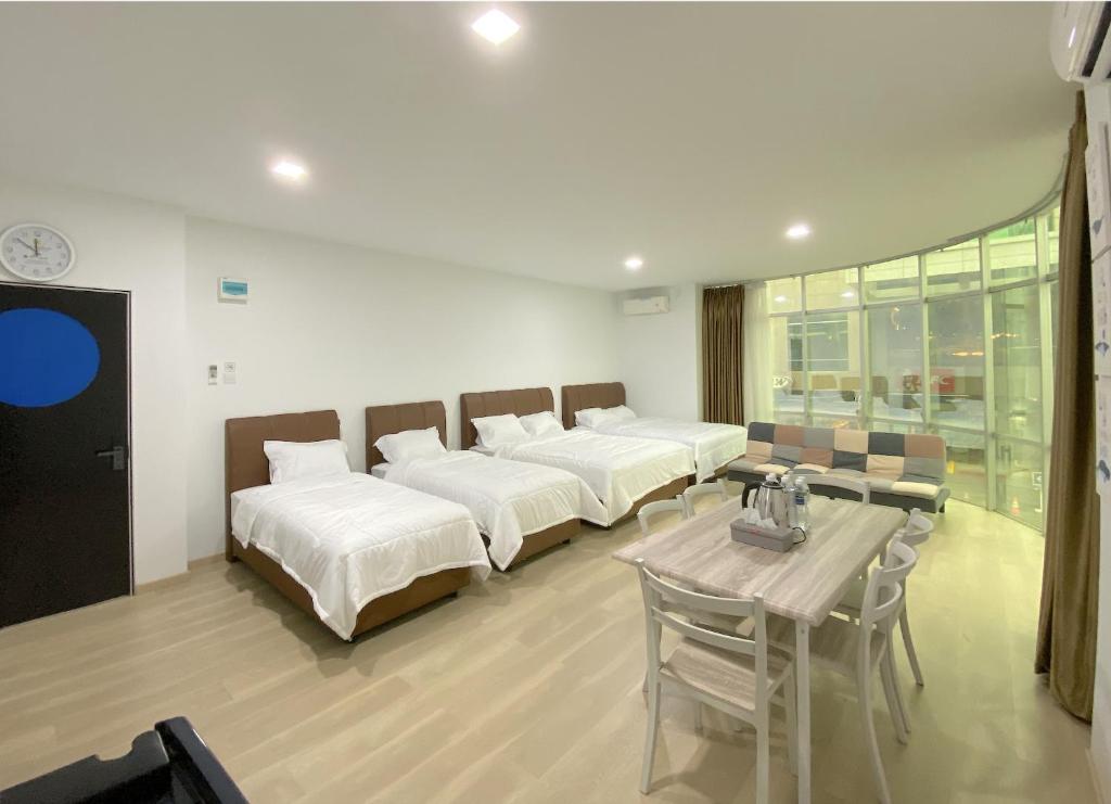 a room with four beds and a table with chairs at CN Homestay A2 Floor 1 at Nagoya Hill Mall in Nagoya