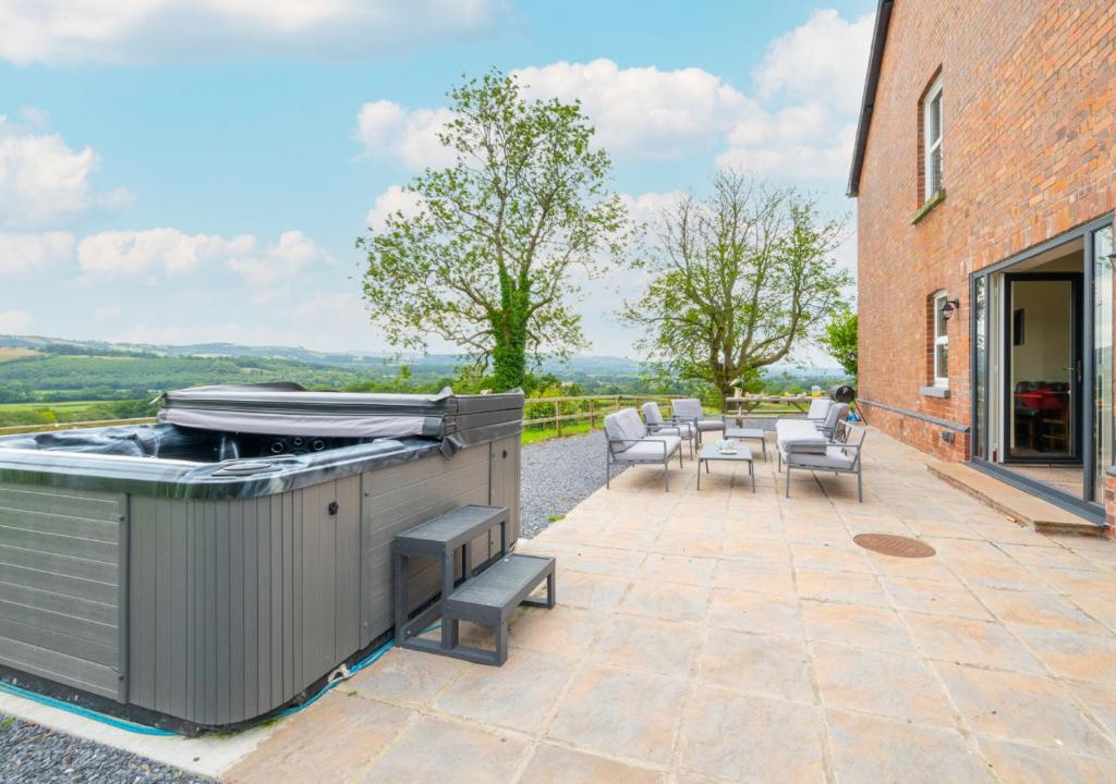 an outdoor patio with a grill and tables and chairs at Greengrove Farmhouse Glasallt in Llangadog