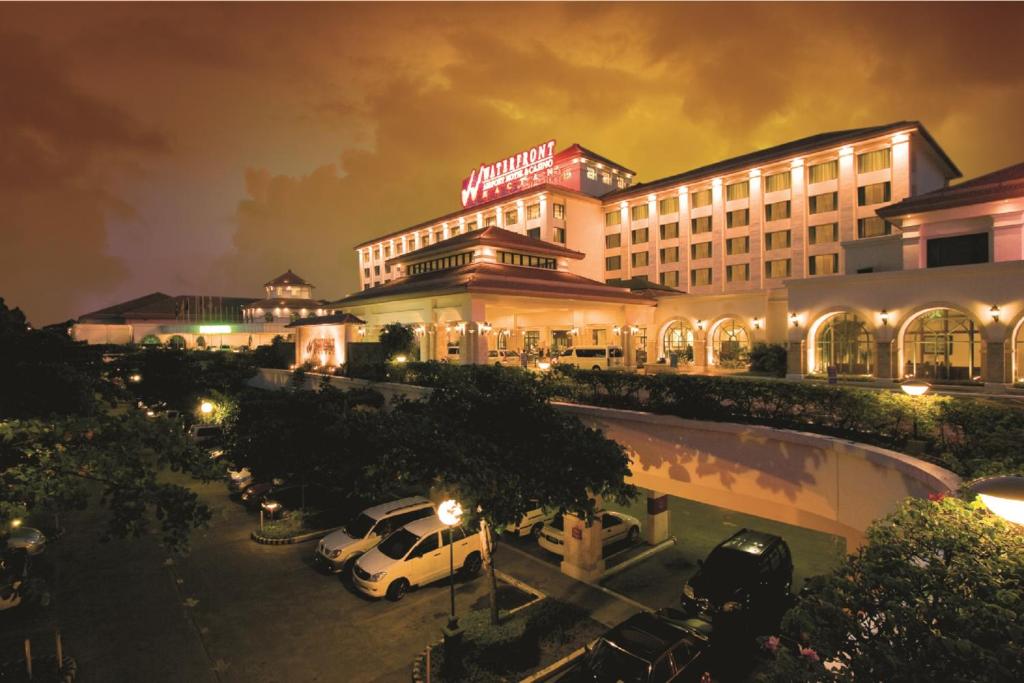 a hotel with cars parked in a parking lot at night at Waterfront Airport Hotel and Casino in Mactan