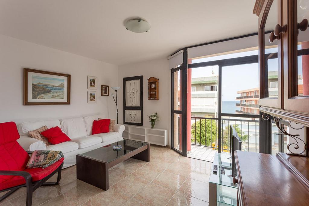 a living room with a white couch and red pillows at Cute Apartment in Salinetas Beach. in Salinetas