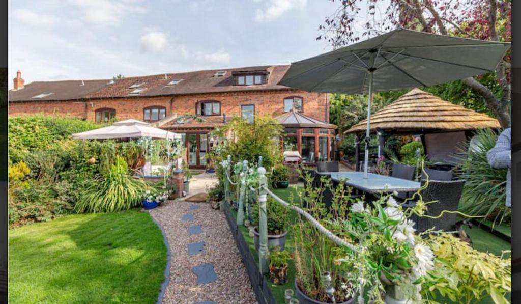 a garden with a table and an umbrella at Home in the Vale Of Evesham in Pershore
