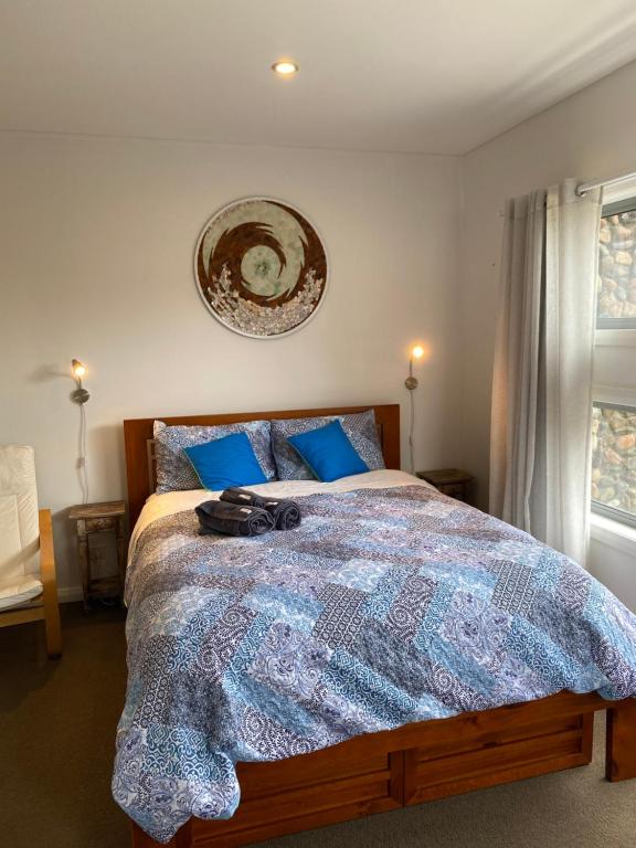 a bedroom with a large bed with blue pillows at Serenity Lodge for Couples in Ulladulla