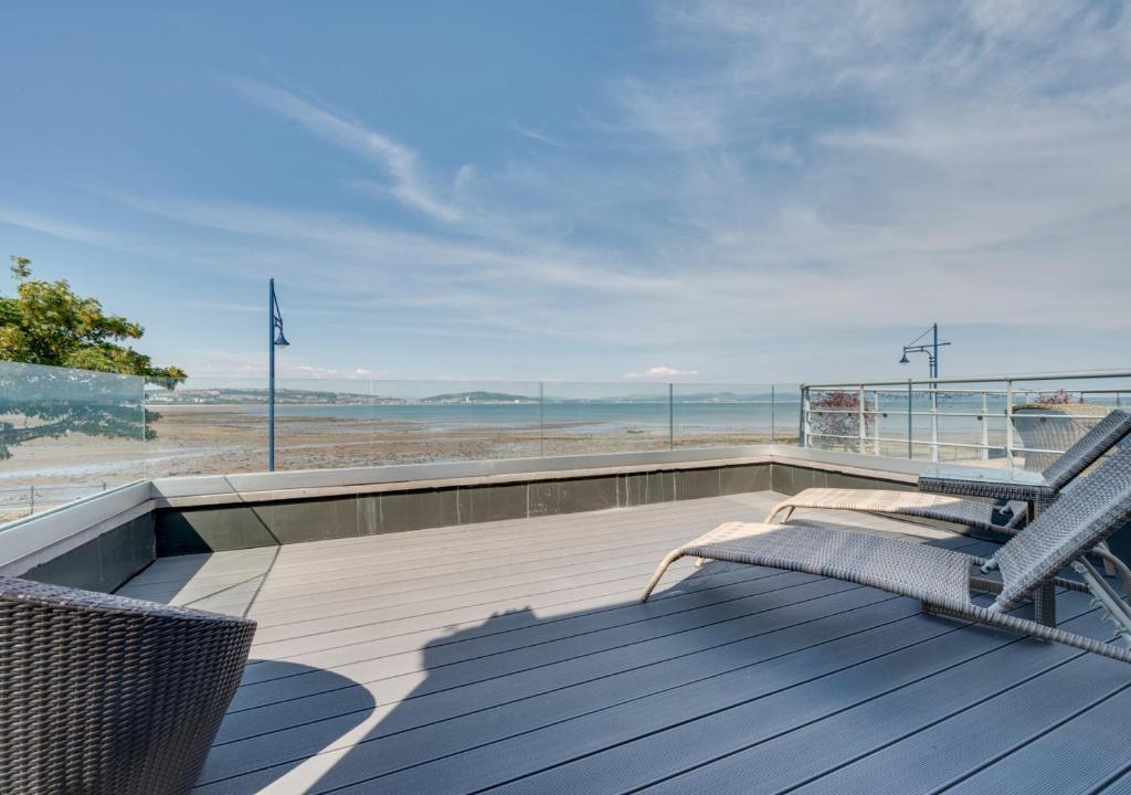een terras met een bank en uitzicht op het strand bij Devon Place in The Mumbles