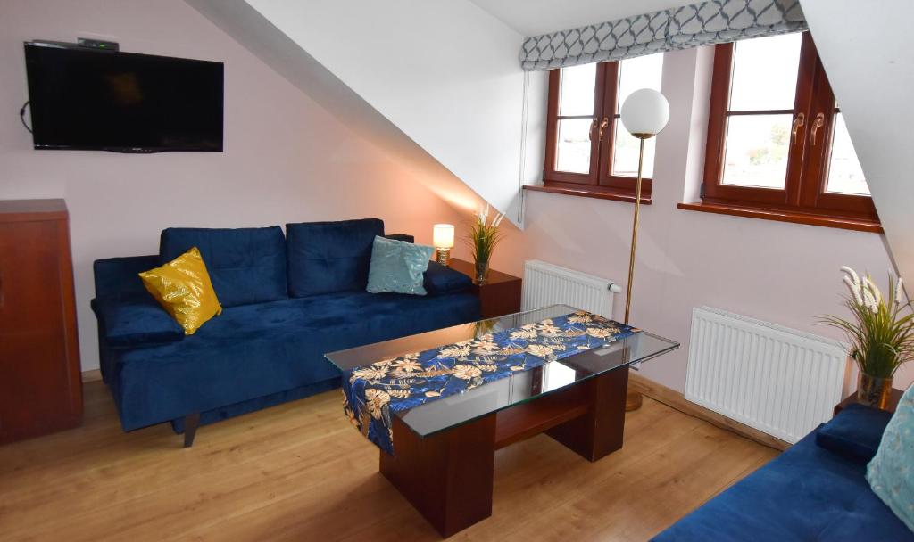 ein Wohnzimmer mit einem blauen Sofa und einem Tisch in der Unterkunft APARTAMENTY TR 11 Apartament nr 6 in Olsztyn