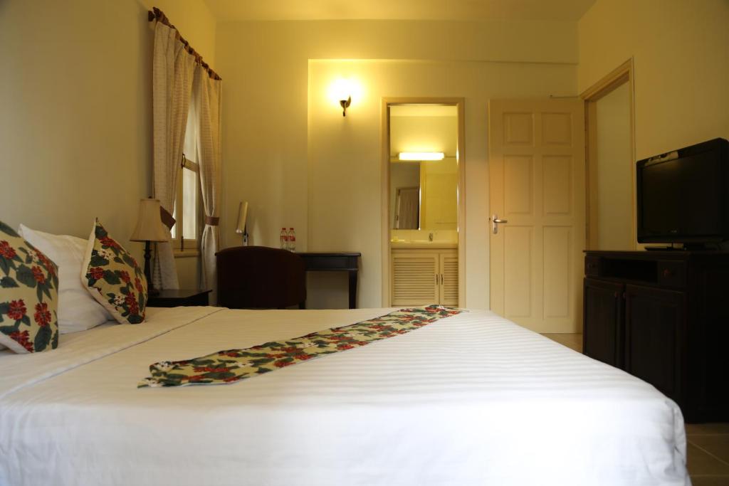 a bedroom with a white bed and a television at Grand Residence in Phnom Penh