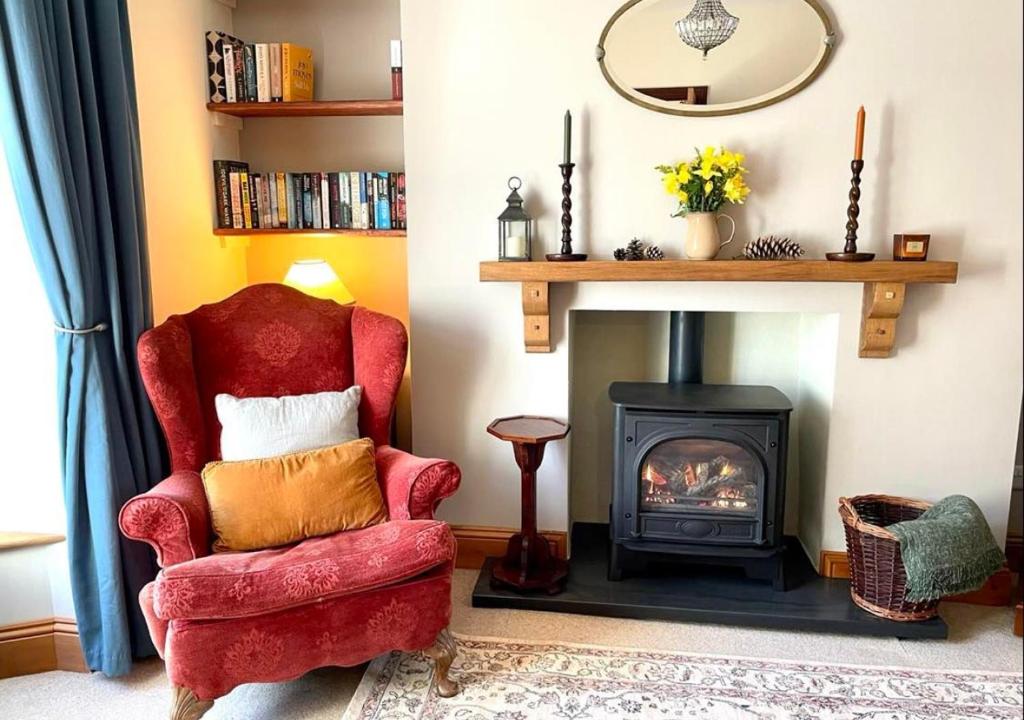 a living room with a red chair and a fireplace at Glancoegen in Cemmaes
