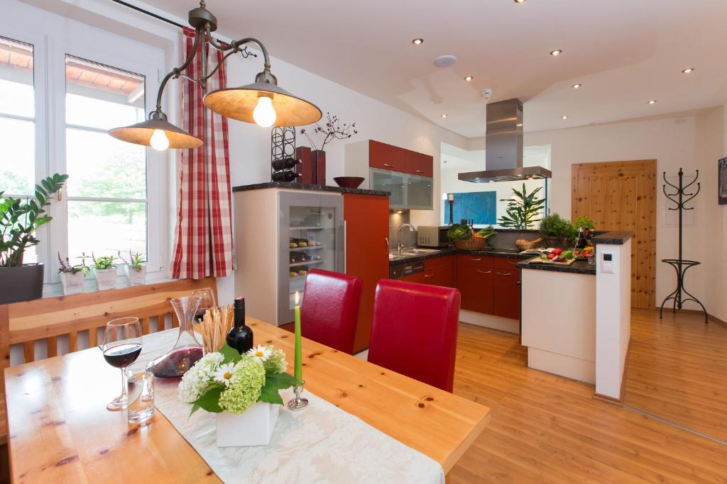 a kitchen and dining room with a wooden table and red chairs at Komfort Appartements Zirbenland - adults only - no dogs in Weißkirchen in Steiermark