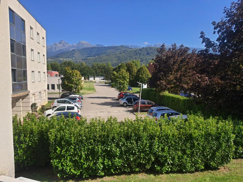 a row of cars parked in a parking lot next to a building at Studio au calme dans résidence Gauguin pour location courte durée et étudiants in Gières