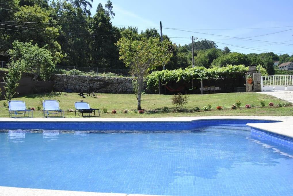 una piscina azul con 2 sillas y un patio en Casa da Buxeira . Entorno magico., 