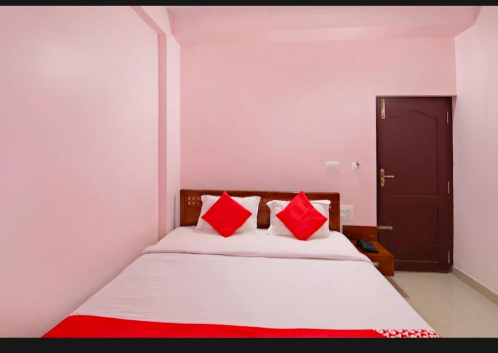 1 dormitorio con cama blanca y almohadas rojas en Royal Guest Inn HSR Layout en Bangalore