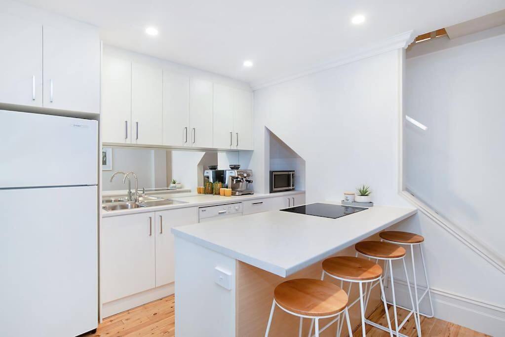 a kitchen with white cabinets and a counter with stools at Modern Central China town Home - Free Carpark in Adelaide
